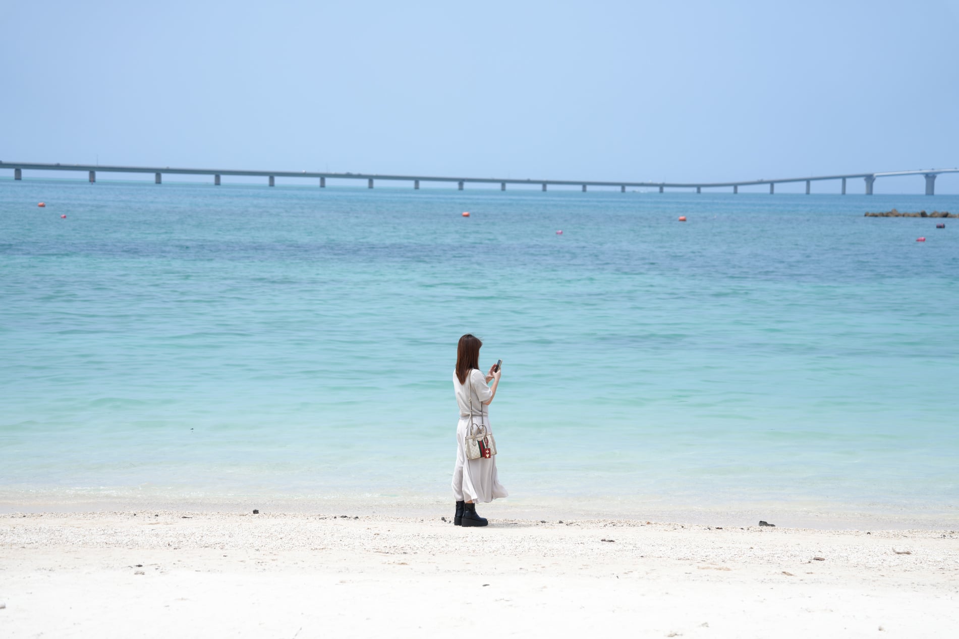 青い海辺に立つ女性